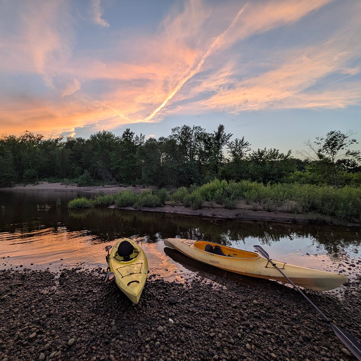 Brilliant sunset over two kayaks on a rocky beach of Bean Island, Eau Claire, Wisconsin